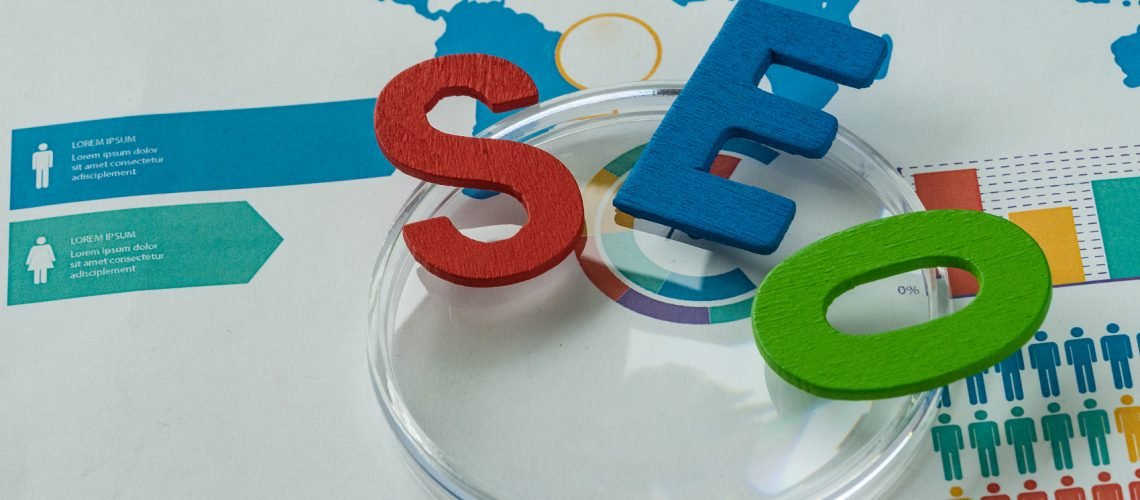 Search engine optimization concept as colorful alphabet abbreviation SEO on magnification glass on printed analysis chart and graph.